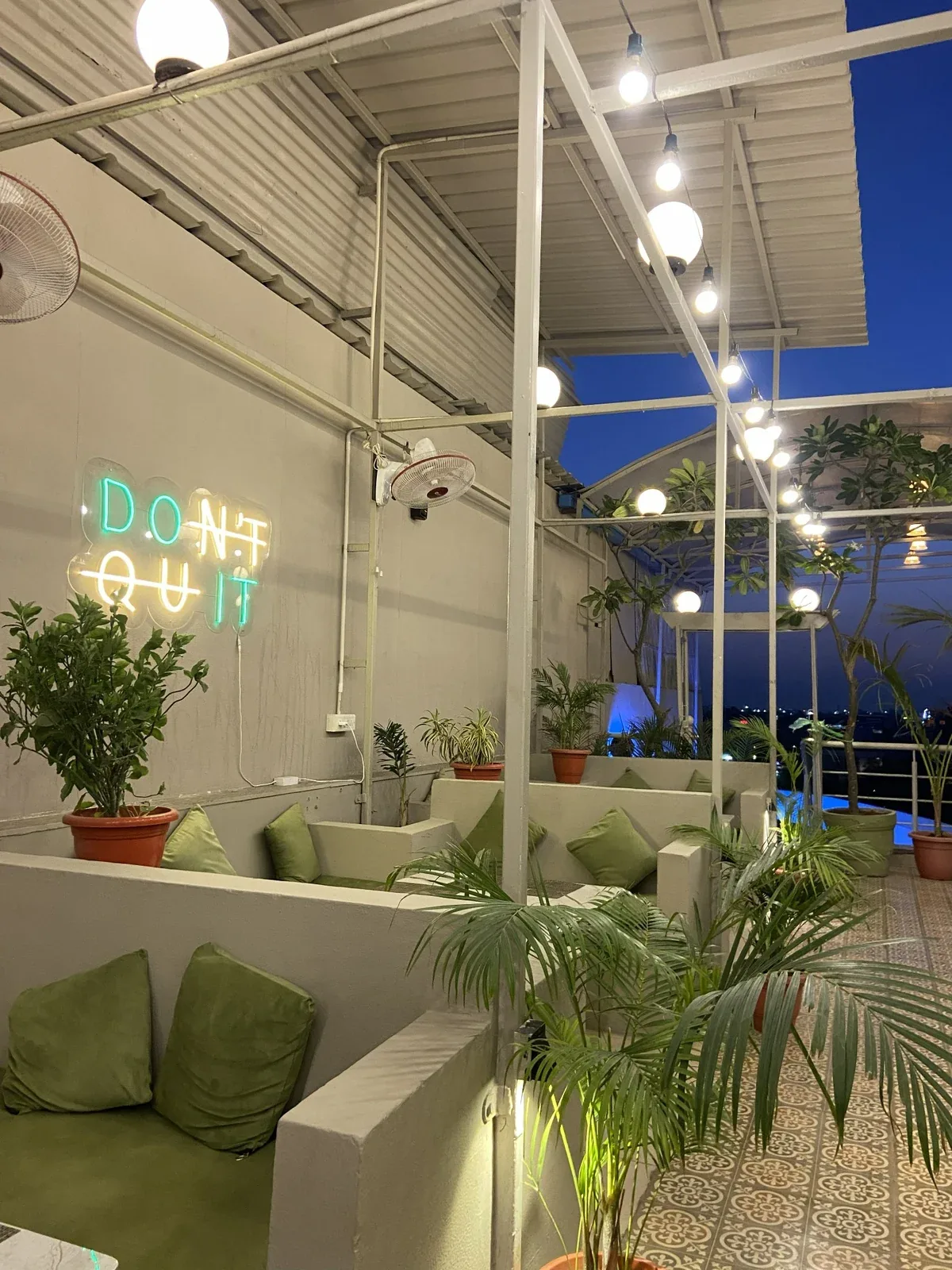 Side seating with planters and warm lights at Chairish Cafe
